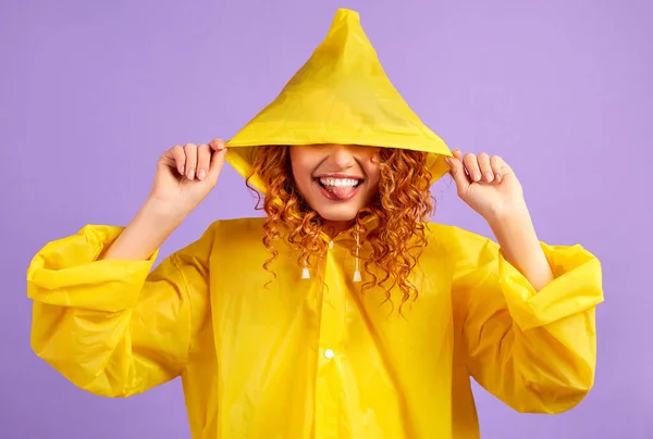 Mulher Ruiva Capa Chuva Amarela Faz Rostos Isolados Fundo Roxo — Fotografia de Stock