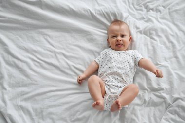 Beyaz güneşli yatak odasında sevimli bir erkek bebek. Yeni doğmuş çocuk yatakta dinleniyor. Küçük çocuklar için çocuk odası. Çocuklar için tekstil ve yatak. Aile sabahı evde. Karnında yeni doğan çocuk..