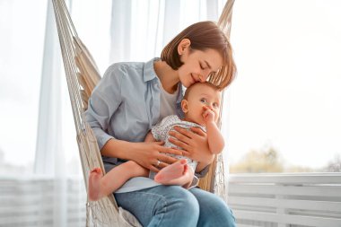 Sevgi dolu bir anne, yeni doğmuş bebeğini evde taşıyor. Anne ve çocuğu bir hamakta. Anne ve bebek güneşli yatak odasında oynuyorlar. Ebeveyn ve küçük çocuk evde dinleniyor. Aile birlikte eğleniyor..