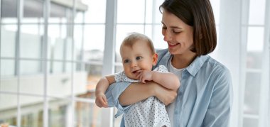 Sevgi dolu bir anne, yeni doğmuş bebeğini evde taşıyor. Anne ve oğlu güneşli yatak odasında oynuyorlar. Ebeveyn ve küçük çocuk evde dinleniyor. Aile birlikte eğleniyor. Çocuk bakımı, annelik kavramı.