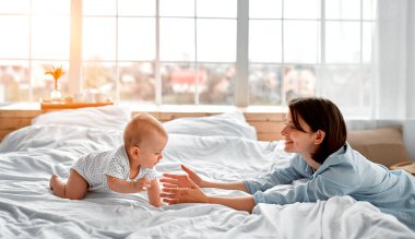 Sevgi dolu bir anne, yeni doğmuş bebeğini evde taşıyor. Anne ve oğlu güneşli yatak odasında oynuyorlar. Ebeveyn ve küçük çocuk evde dinleniyor. Aile birlikte eğleniyor. Çocuk bakımı, annelik kavramı.