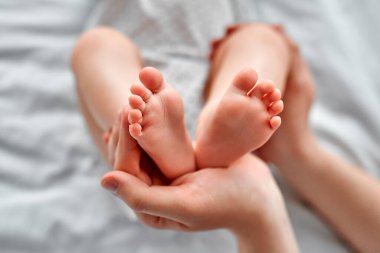 Yeni doğmuş bebeğinin küçük ayaklarıyla nazikçe okşayan mükemmel ciltli bir kadın. Aile mutluluğu ve küçük çocuklu sevgi dolu ebeveynler..