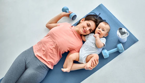 A sports mother is engaged with the child in fitness and yoga at home. The concept of sports, motherhood and an active lifestyle. Young woman in sports training with her child.