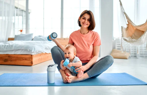 Sporcu bir anne evde yoga ve spor salonunda çocukla meşgul olur. Spor konsepti, annelik ve aktif yaşam tarzı. Çocuğuyla spor eğitimi alan genç bir kadın..