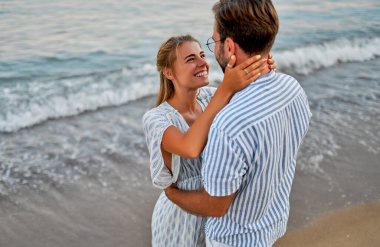 Sevgi dolu genç bir çift sahilde sarılıyor, birbirlerini seviyorlar ve tatillerinde kumsalda romantik bir şekilde vakit geçiriyorlar..