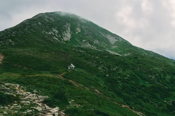 草や石で覆われた山岳地帯の風景 山の中の家 霧と雲に覆われた山 — ストック写真