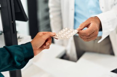 Bir eczacının tezgahtaki kadın müşteriye bir paket beyaz hap vermesi. Ellere odaklan. Konsept: Eczane, ilaç, sağlık, hizmet.