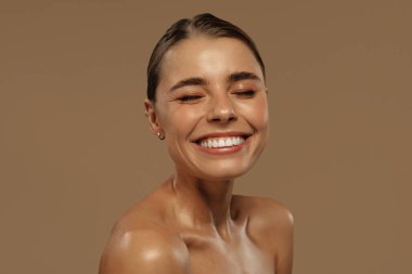 Sırt sırta verip, kameraya güvenle bakan parlak, sağlıklı cilde sahip iki genç kadın. Bej arka planda doğal güzellik ve cilt bakımı. Minimalist estetik. Güzellik ve sağlık konsepti.