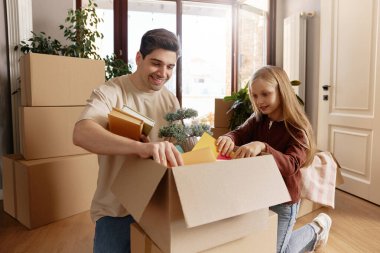 Gülümseyen baba ve kızı yeni bir eve taşındıktan sonra birlikte kutuları boşaltıyor. Kitap ve dekorasyon bulurlar, sürecin tadını çıkarırlar. Kavram: Aile bağı, taşınma, birliktelik.