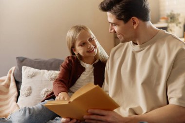 Gülümseyen baba ve kız, sıcak bir oturma odasında Golden Retriever 'larıyla hassas bir anın tadını çıkarıyorlar. Köpek sakin ve rahat görünüyor. Konsept: Aile sevgisi, evcil hayvan arkadaşlığı, ev konforu.