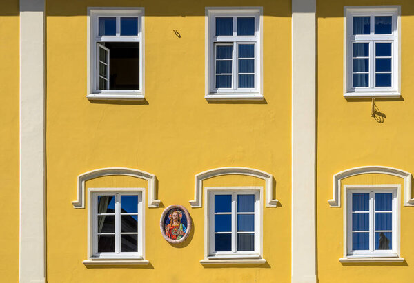 Yellow front of a bourgeois house with image of jesus christus in Lienz, Austria