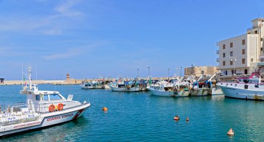 Guarda Costiera (Sahil Güvenlik) teknesi ve İtalya 'nın Monopoly kentindeki rıhtımda birkaç balıkçı teknesi olan liman.