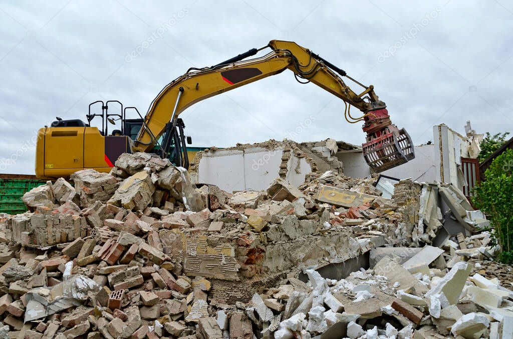demolition of a residential house by a digger with a picker arm on a mountain of rubble in Austria