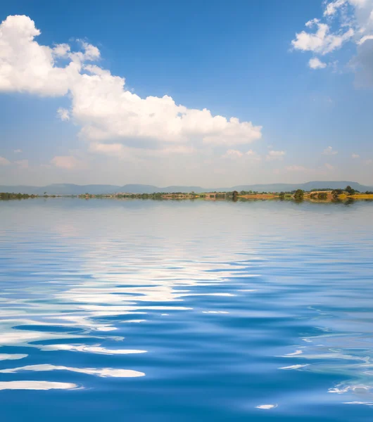 Superficie ondulada de agua con nubes y fondo del cielo —  Fotos de Stock