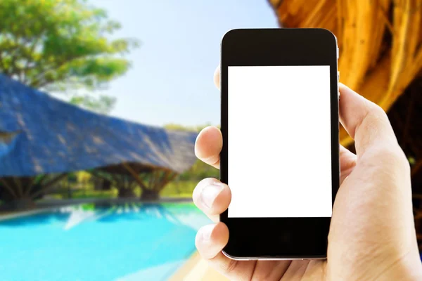 hand holding phone with blurred swimming pool  background