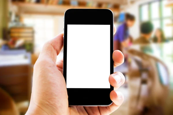 Hand holding phone with blurred cafe  background — Stock Photo, Image