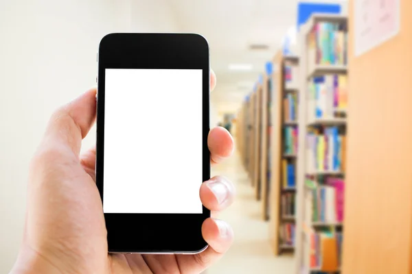 Mano che tiene lo smartphone sullo sfondo della biblioteca — Foto Stock