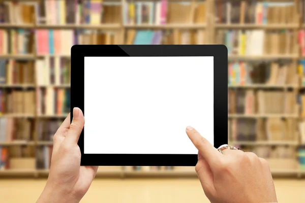 Hand holding digital tablet against bookshelf — Stock Photo, Image