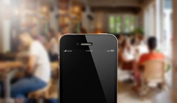 Chiudere smart phone contro persone sfocate in sfondo caffè — Foto Stock