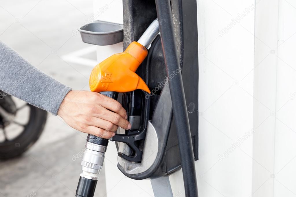 Closeup of woker hand holding gas pump nozzle at gas station.