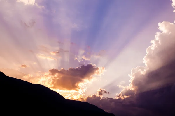 Beautiful dramatic sky with sun rays. over mountain — Stock Photo, Image