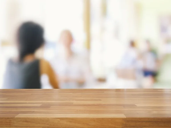 Mesa de madera vacía y gente borrosa en el fondo de la cafetería — Foto de Stock