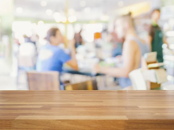 Empty wooden table and blurred people in cafe background — Stock Photo, Image