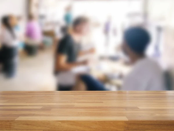 Table en bois vide et personnes floues dans le fond du café — Photo