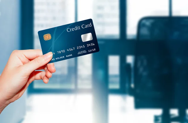 Femme main tenant carte de crédit contre backgro bureau d'affaires — Photo