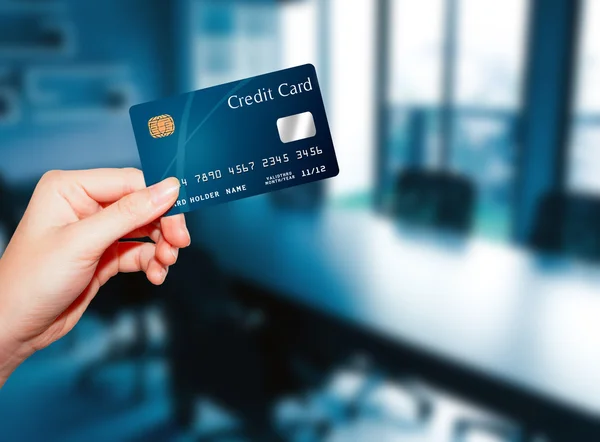 Female  hand holding credit card against business office backgro — Stok fotoğraf