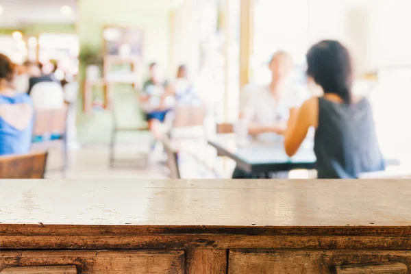 Άδειο ξύλινο τραπέζι και θολή άνθρωποι σε καφέ φόντο — Φωτογραφία Αρχείου
