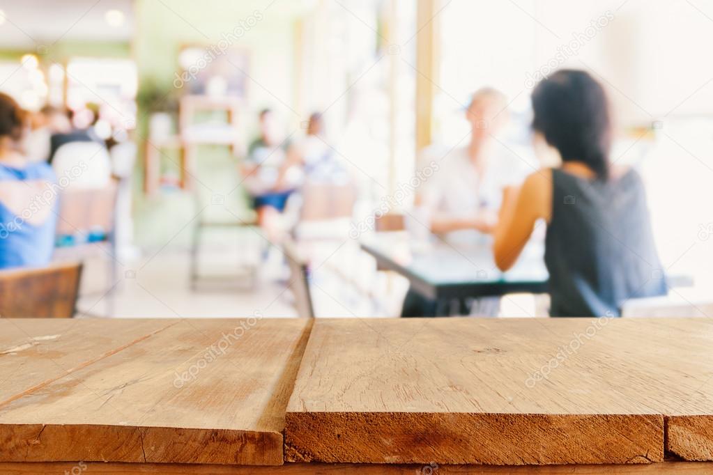 Empty wooden table and blurred people in cafe background