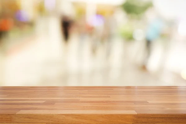 Empty wooden table and blurred people walking at shopping mall b — Stock Photo, Image