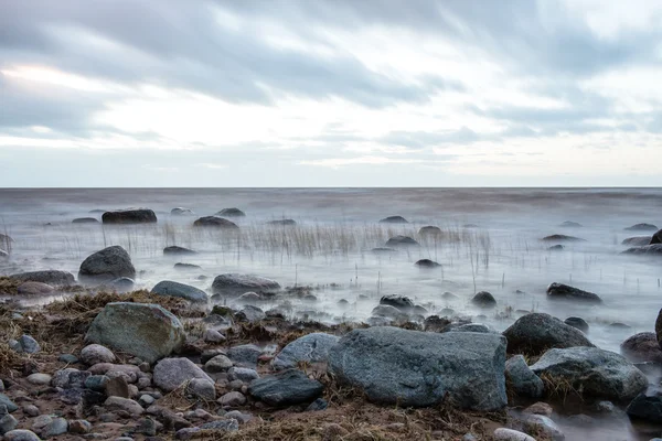 Coucher de soleil au bord de la mer d'une plage avec des rochers — Photo