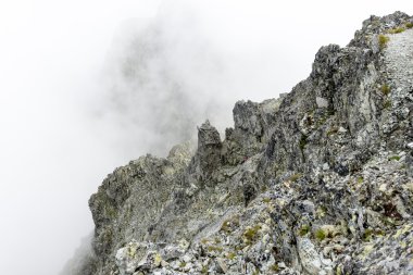 bulutlar ve sis kaplı kayalık dağ manzarası