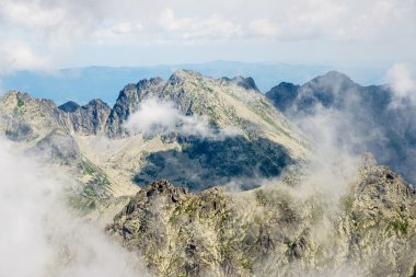 bulutlar ve sis kaplı kayalık dağ manzarası