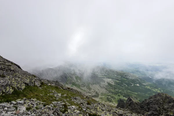 Bulutlar ve sis kaplı kayalık dağ manzarası — Stok fotoğraf