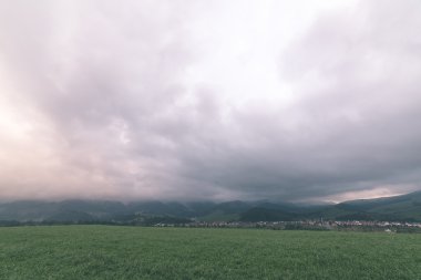Karanlık fırtına bulutları yeşil çim - vintage etkisi ile çayır üzerinde