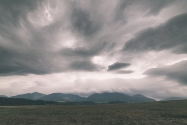 Karanlık fırtına bulutları yeşil çim - vintage etkisi ile çayır üzerinde
