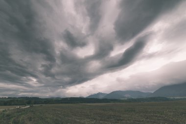 Karanlık fırtına bulutları yeşil çim - vintage etkisi ile çayır üzerinde