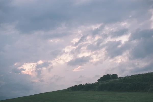 Nuvens tempestade escura sobre o prado com grama verde - efeito vintage — Fotografia de Stock