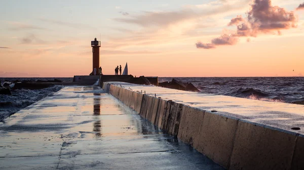 Lighthouse with rusty metal rails near sea port and silhouettes — Stock Photo, Image