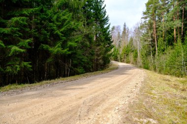 Yazın toprak yol kenarları çimlerle kaplı, perspektifli çakıl taşları.