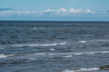Fırtınadan önce beyaz kum ve mavi suyla deniz kıyısı. Beyaz başlı dalgalar