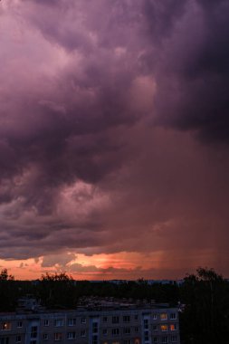 Tarlaların ve şehirlerin üzerinde dramatik, kırmızı, karanlık, dramatik bulutlar var.