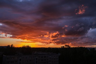 Tarlaların ve şehirlerin üzerinde dramatik, kırmızı, karanlık, dramatik bulutlar var.