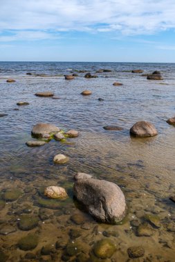 Deniz kenarındaki boş kumlu kumsalda kayalar ve mavi gökyüzü. sessiz meditasyon arkaplanı
