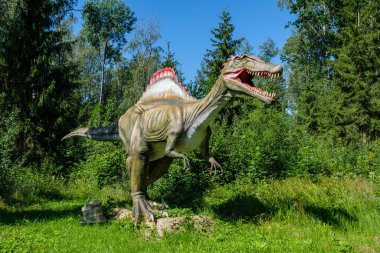 Yapay dinozorlar ve parktaki antik sürüngen heykelleri yaz yeşili ortamda