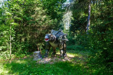 Yapay dinozorlar ve parktaki antik sürüngen heykelleri yaz yeşili ortamda