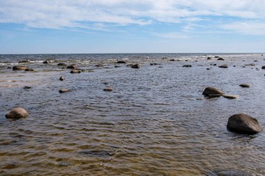 Deniz kenarındaki boş kumlu kumsalda kayalar ve mavi gökyüzü. sessiz meditasyon arkaplanı